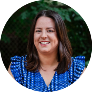 Simone Carvalho smiling in a blue shirt with white polka dots against a green leafy background